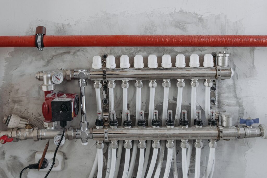 A plumbing manifold with red supply pipe and a circulating pump