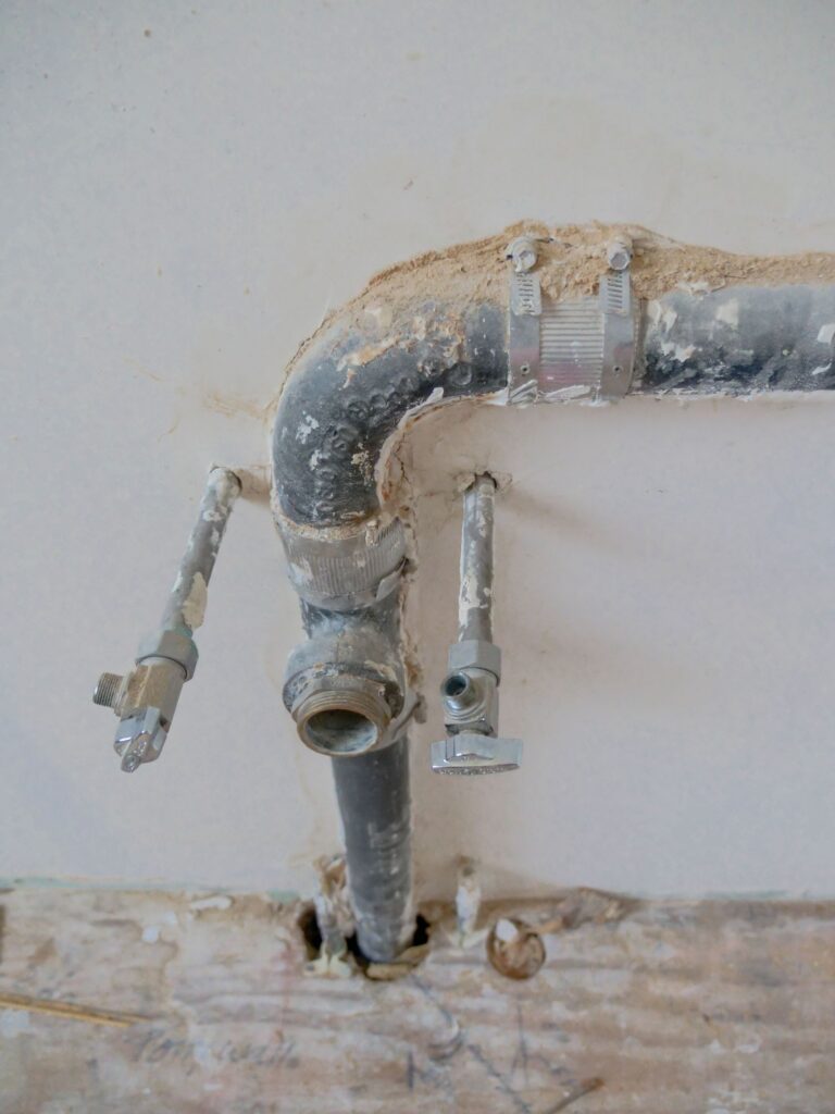 Older galvanised water pipe and a shutoff on a wall