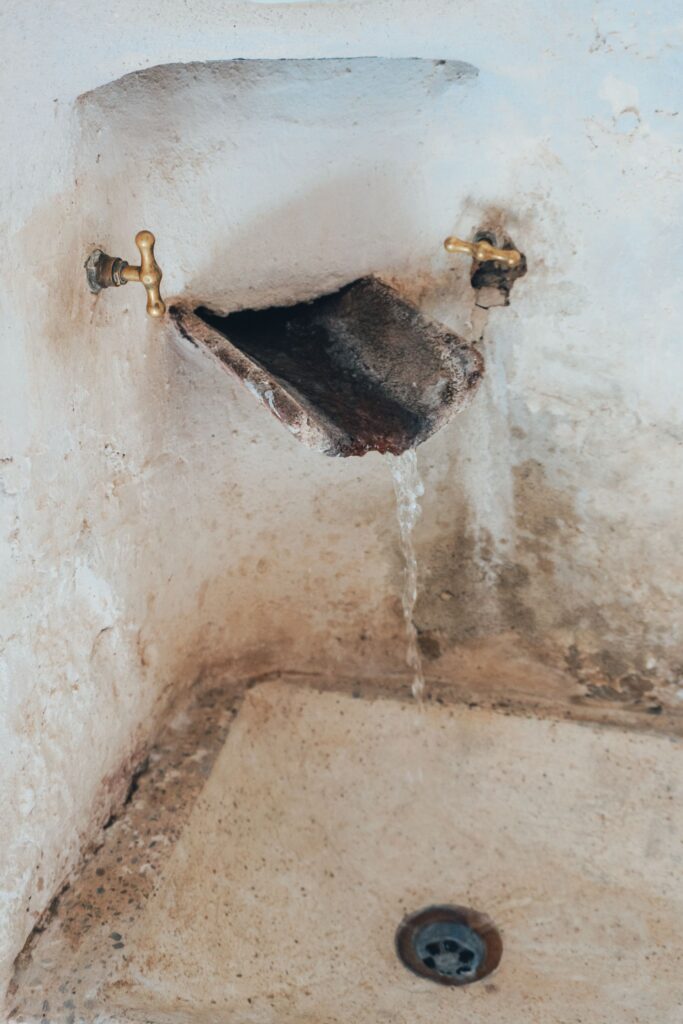 An older tap running into a weathered sink
