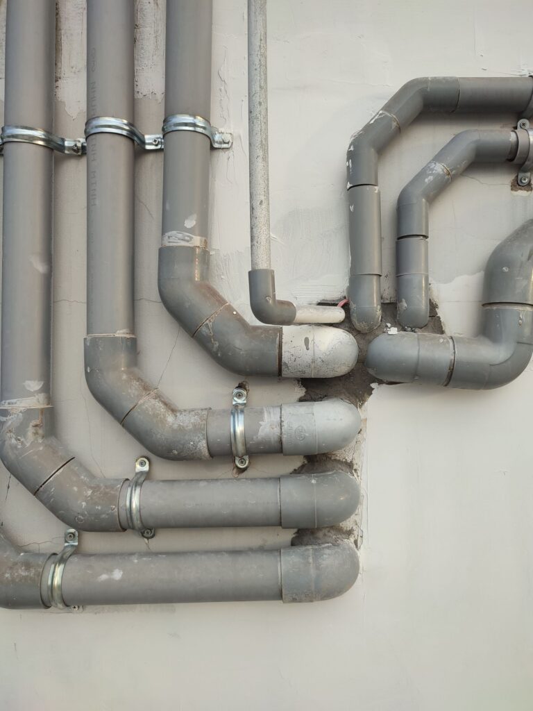 Grey plastic waste pipes running across a wall