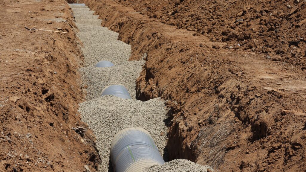 A new sewer line bedded in gravel along an open trench