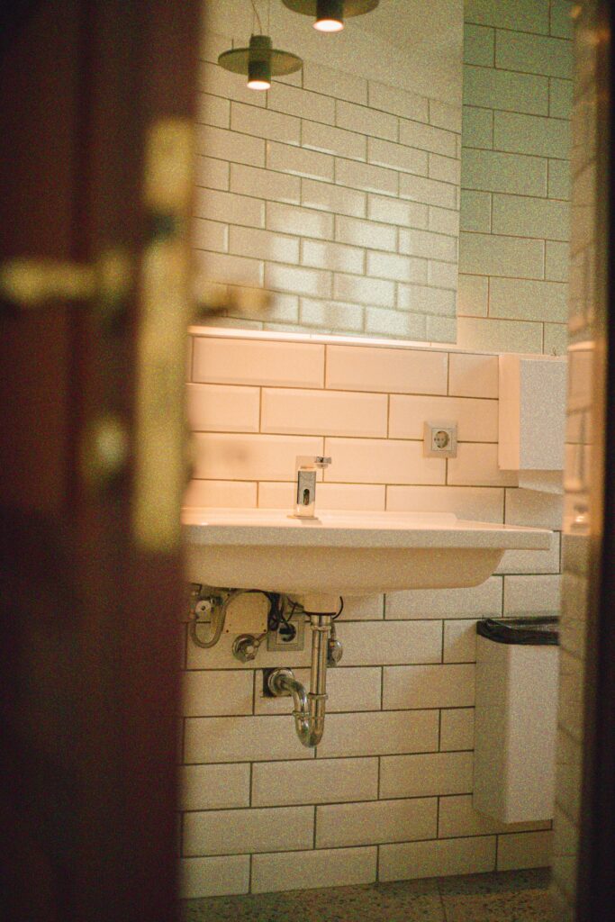 A tiled utility room with a wall hung sink and tap
