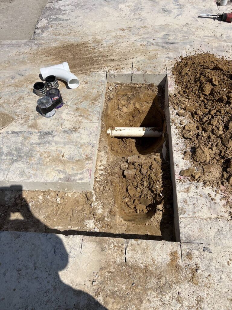 A concrete saw cut opened to reach a pipe under the slab