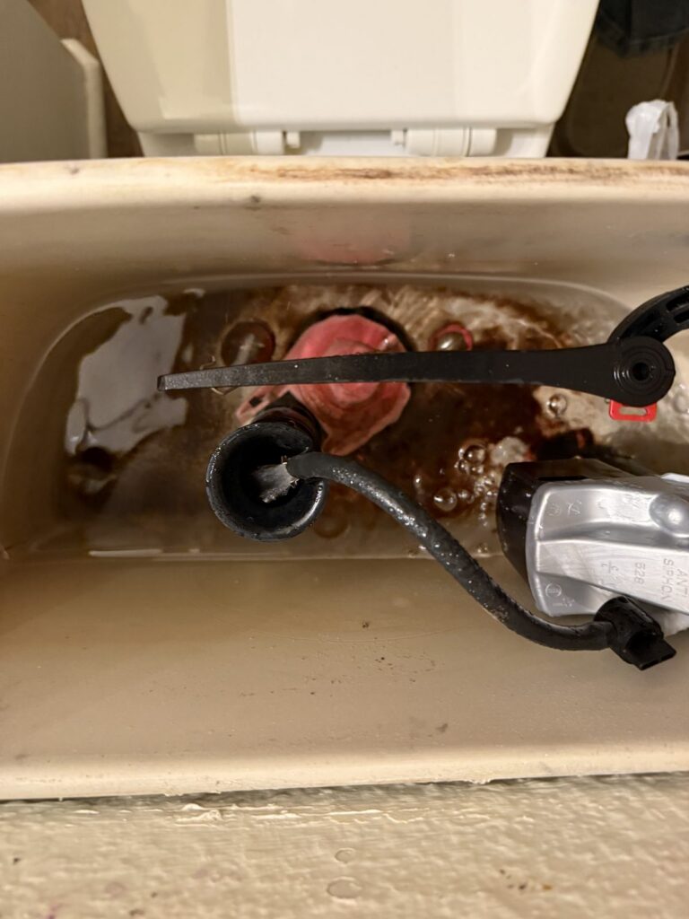 The inside of a toilet tank showing corroded and failing parts